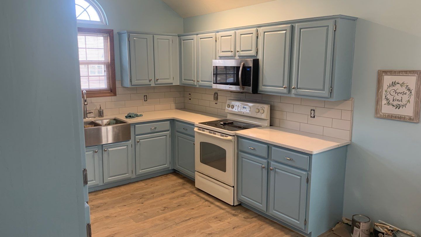 A kitchen room with dusty blue painted cabinets- Overland Park, KS painting services