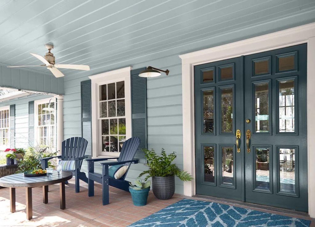 A blue painted porch with chairs and a rug- Exterior House Painting Services in Lawrence, KS