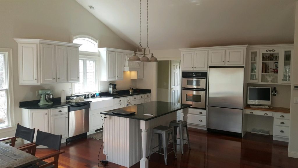 A kitchen with white cabinets and black marble countertop- Cabinet Painters in Overland Park, KS